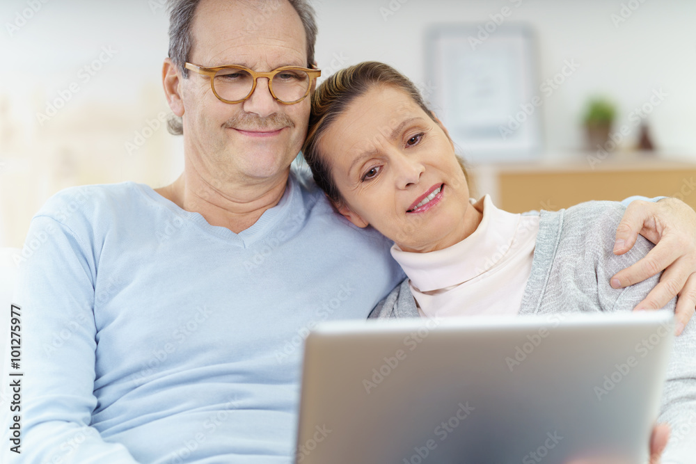 älteres paar liegt gemütlich auf dem sofa und schaut auf den laptop