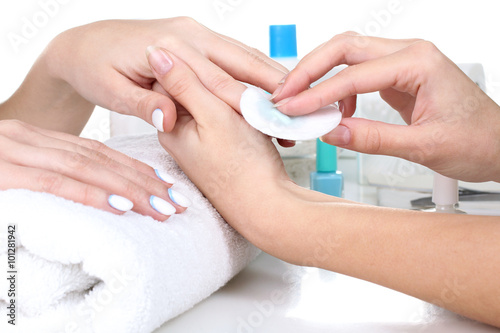 Closeup shot of a woman in a nail salon receiving a manicure by a beautician with cotton wool with acetone. Woman getting nail manicure. Beautician file nails to a customer. photo
