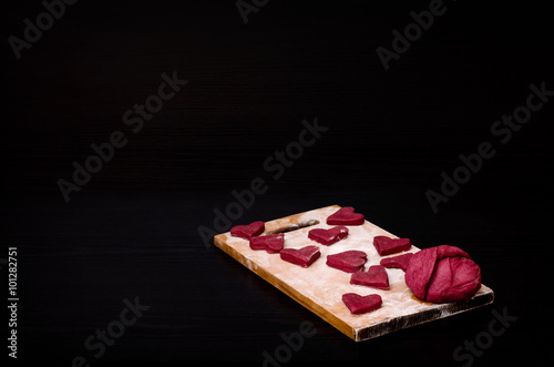 Red heart-shaped cookies on a wooden plank, baking the day of Valentine's