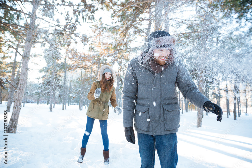 Cheerful woman playing snowballs with her boyfriend