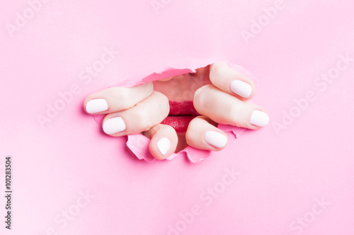 Woman ripping pink cardboard and showing beautiful red lips