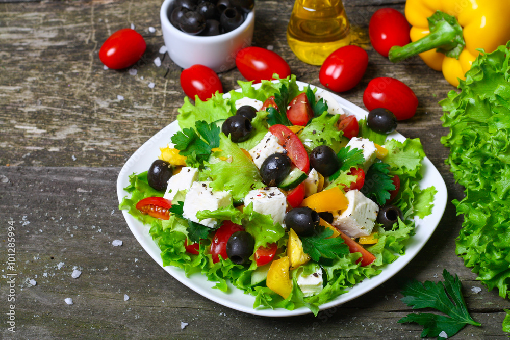 Greek salad with fresh vegetables, feta cheese and black olives on a wooden background Greek salad with fresh vegetables, feta cheese and black olives on a wooden background