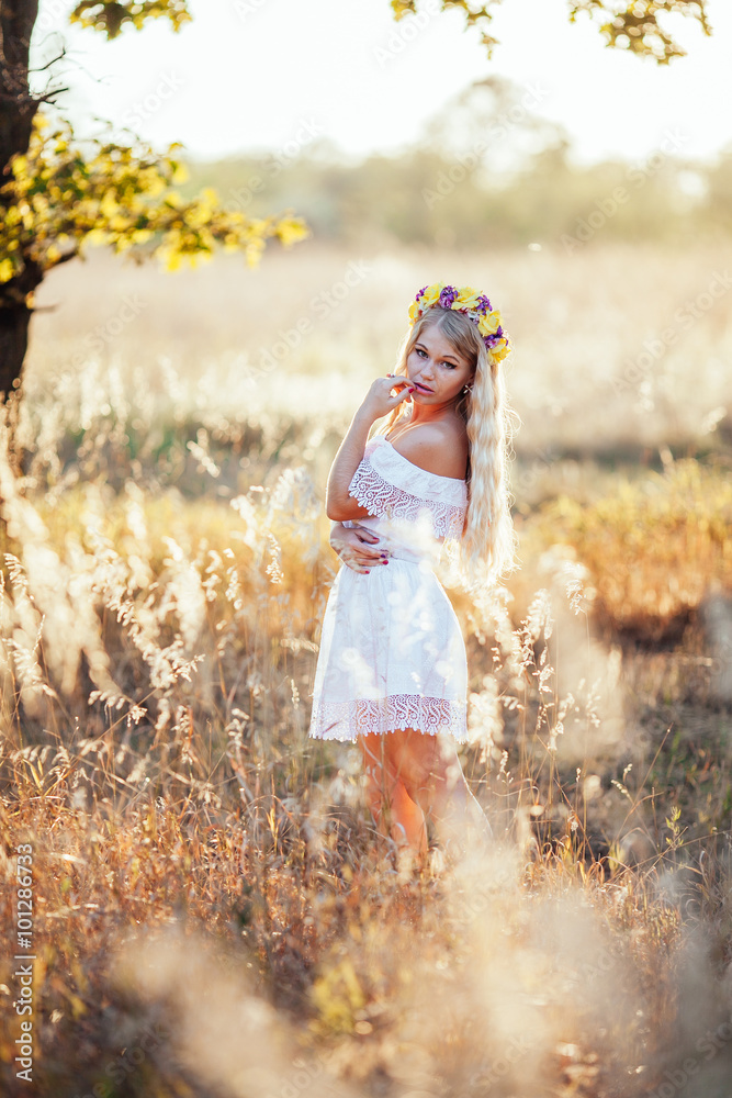 Portrait of blonde girl wearing  white dress with flower wreath
