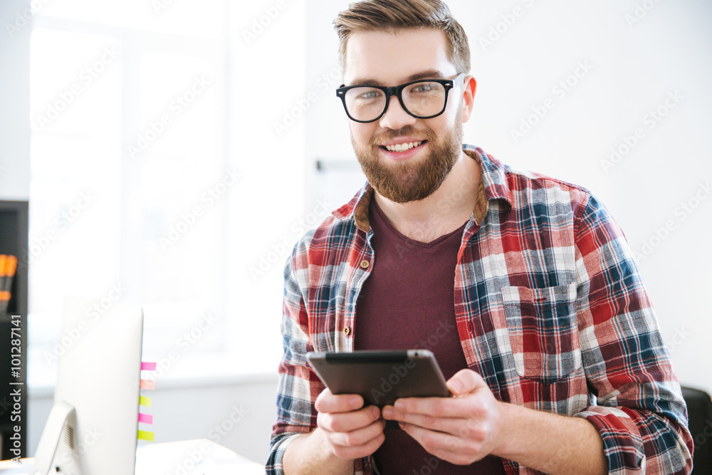 Happy handsome bearded male in glasses using tablet Happy handsome bearded male in glasses using tablet