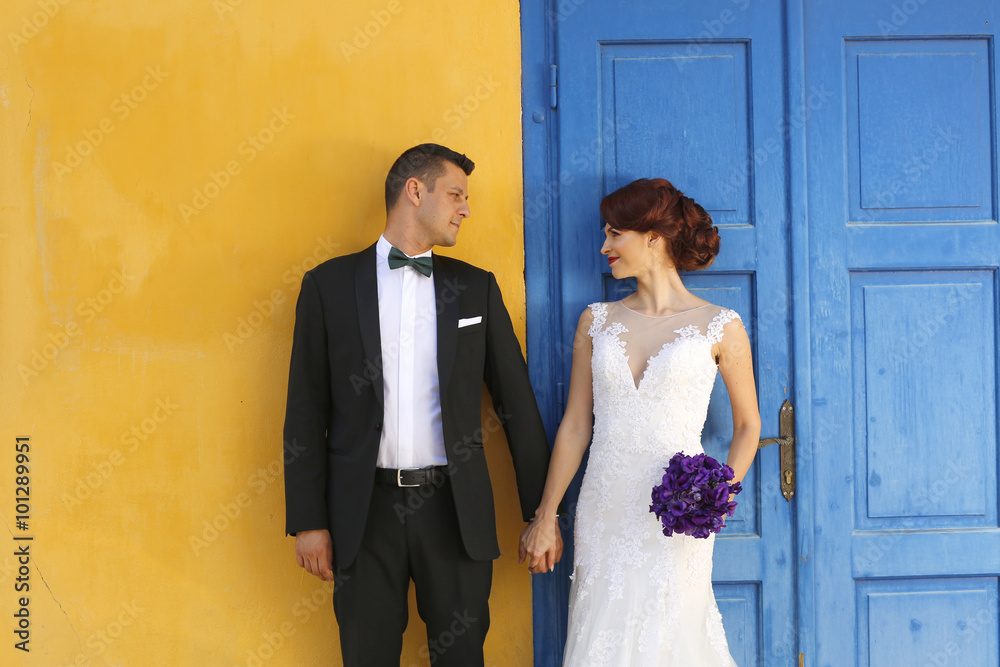 groom and bride posing against a blue and yellow wall groom and bride posing against a blue and yellow wall
