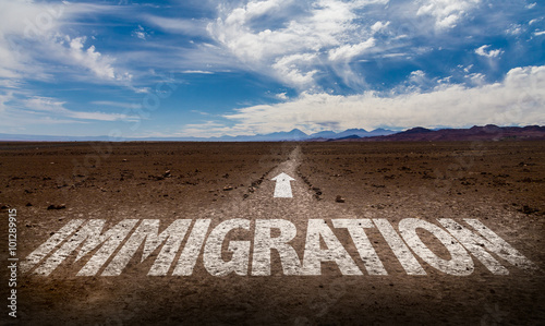 Fotografi Immigration written on desert road