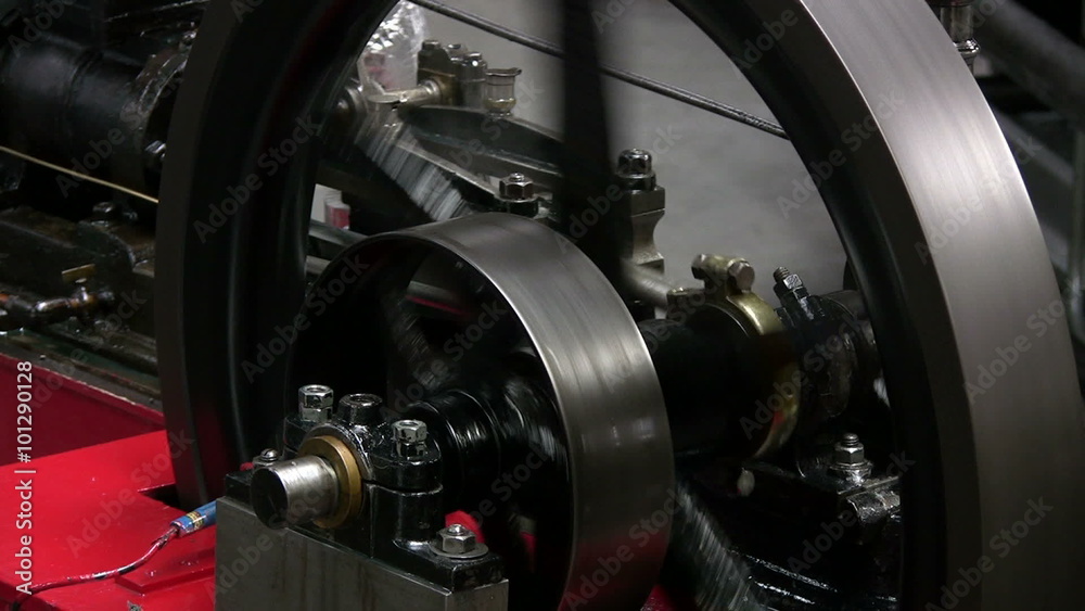 Stationary steam engine flywheel and eccentric valve gear showing the operation of the eccentric cam just behind the flywheel which operates the valve gear.