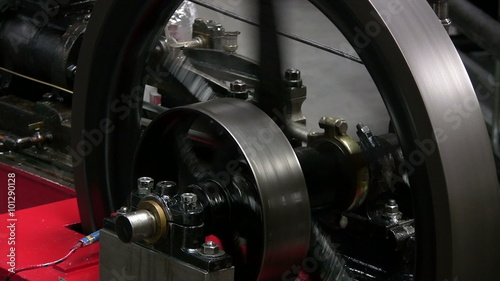 Stationary steam engine flywheel and eccentric valve gear showing the operation of the eccentric cam just behind the flywheel which operates the valve gear.