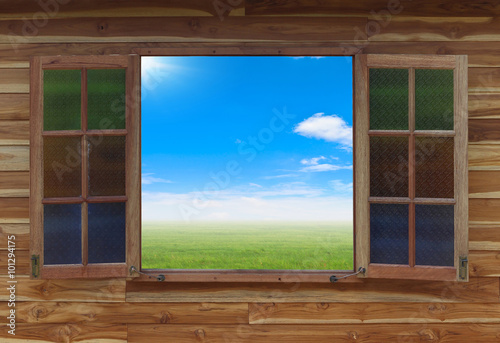 Open window with green field under blue sky on a background