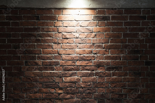 Grungy dark red brick wall with spotlight, texture