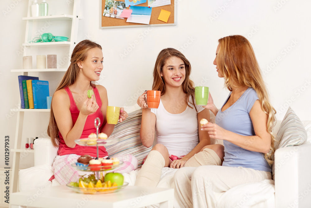 happy young women drinking tea with sweets at home