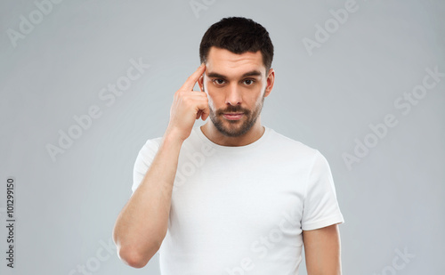 man with finger at temple over gray background