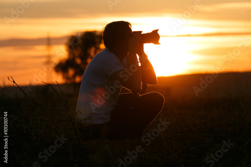 Fotograf fotografiert Sonnenuntergang und Landschaft Silhouette photo