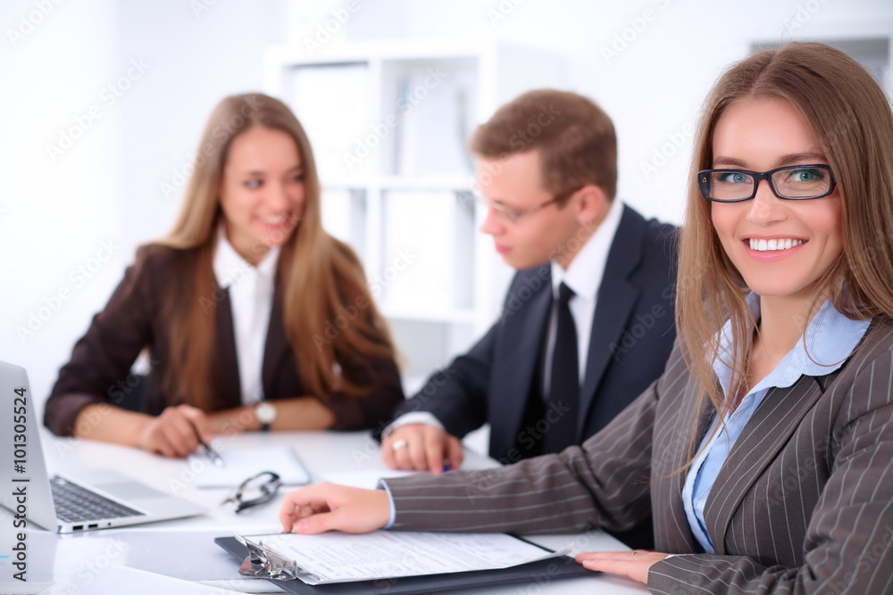 A group of business people at a meeting on the background of office. Focus on a beautiful brunette A group of business people at a meeting on the background of office. Focus on a beautiful brunette
