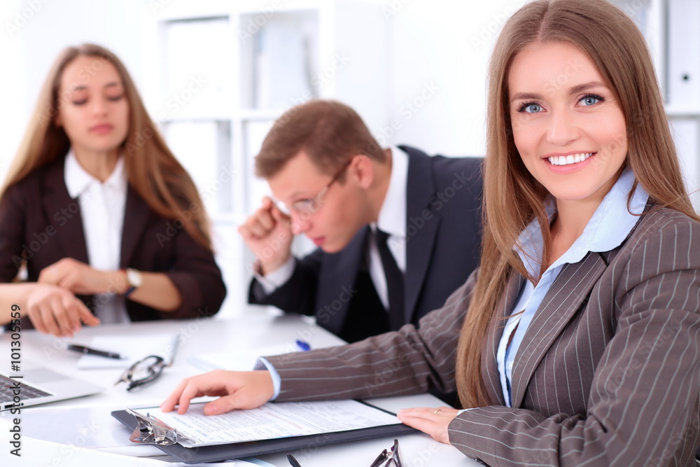 A group of business people at a meeting on the background of office. Focus on a beautiful brunette A group of business people at a meeting on the background of office. Focus on a beautiful brunette