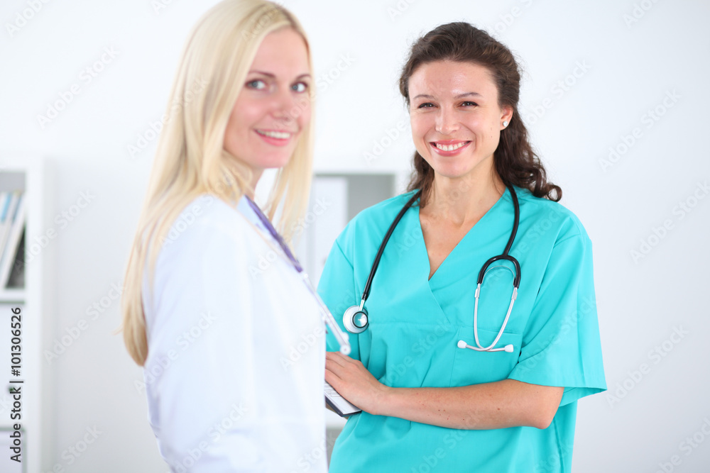 Two confident friendly female doctors sitting at the table and listen to the patient's history . Medical and health care concept Two confident friendly female doctors sitting at the table and listen to the patient's history . Medical and health care concept