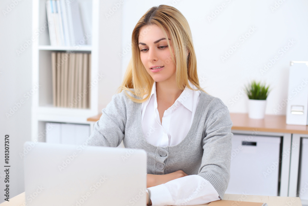 Portrait of young business woman sitting at the desk on office background Portrait of young business woman sitting at the desk on office background