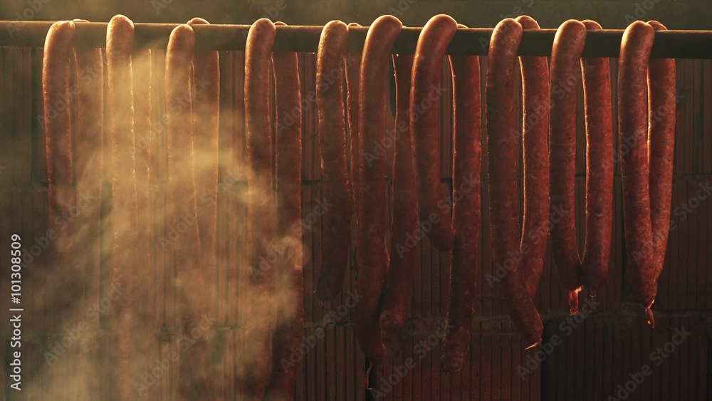 Smoking homemade pork sausages, food preparation process of cured pork meat delicacy in smokehouse.