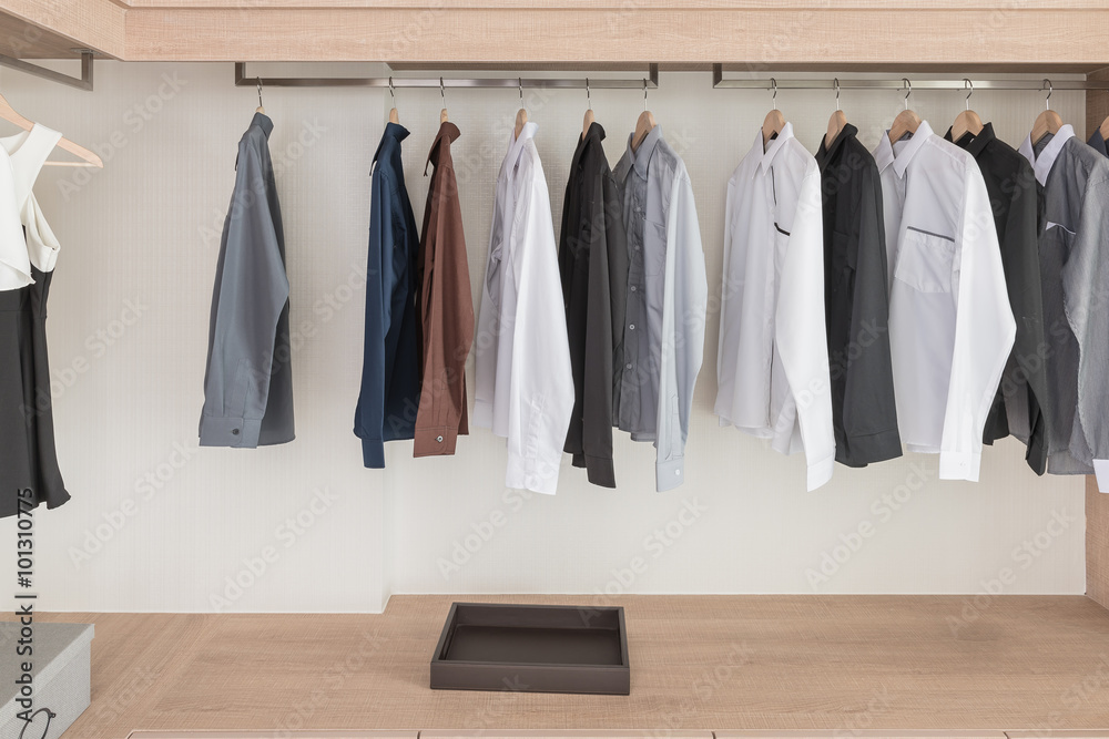 shirts hanging on rail in modern wooden wardrobe