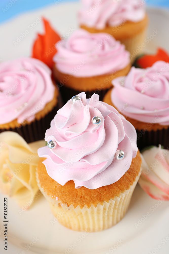 Tasty cupcakes on plate, on color wooden background