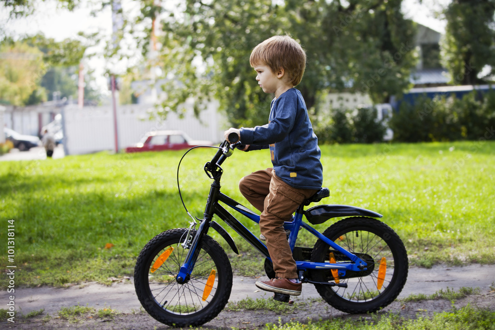 Happy boy ride a bicycle in city park