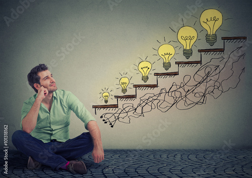 Happy man sitting on a floor in his office dreaming of business education success