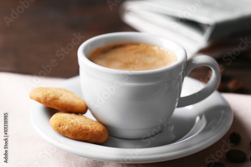 Cup of coffee, cookie and newspaper on wooden table background