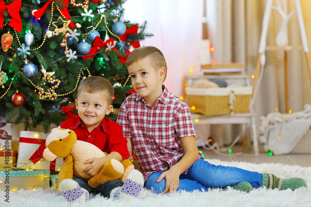 Two cute small brothers with teddy bear on Christmas tree background Two cute small brothers with teddy bear on Christmas tree background