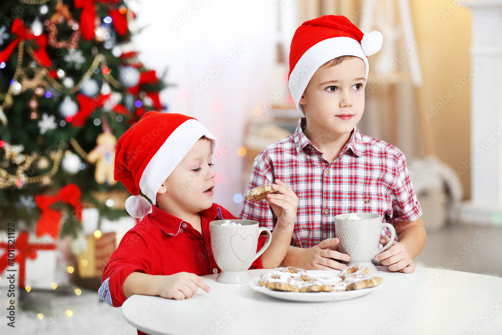 Two cute small brothers eating cookies on Christmas decoration background Two cute small brothers eating cookies on Christmas decoration background