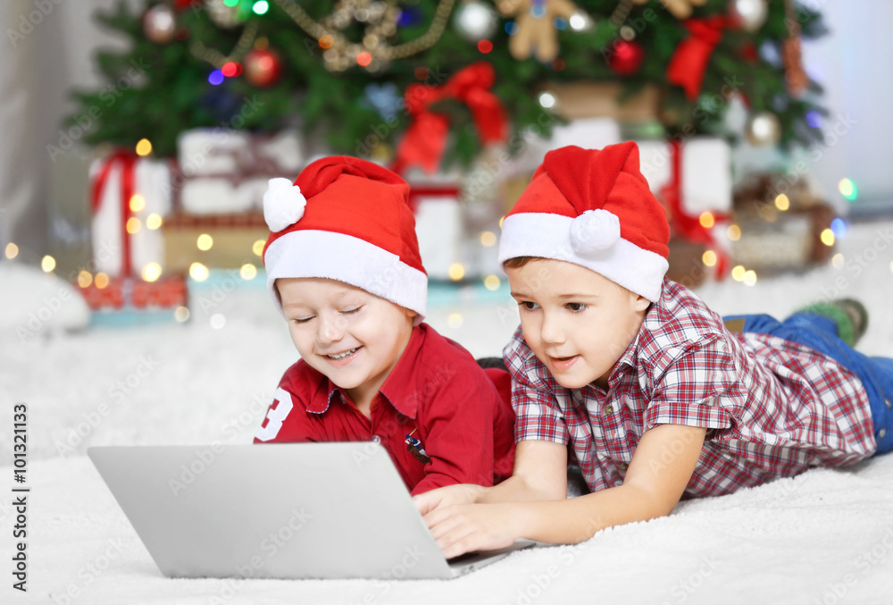 Two cute small brothers using laptop on Christmas decoration background Two cute small brothers using laptop on Christmas decoration background