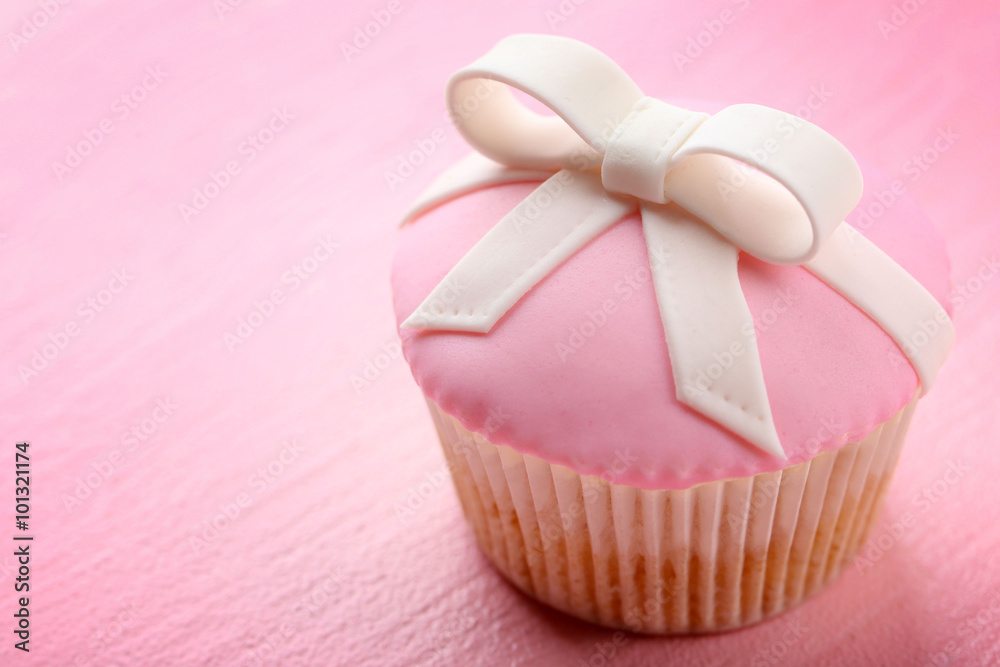 Tasty cupcake with bow on color wooden background Tasty cupcake with bow on color wooden background