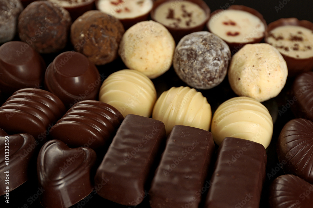Fototapeta premium Assorted chocolate candies on black background, close up