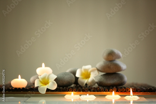 Spa still life with stones  candles and flowers in water on blurred background