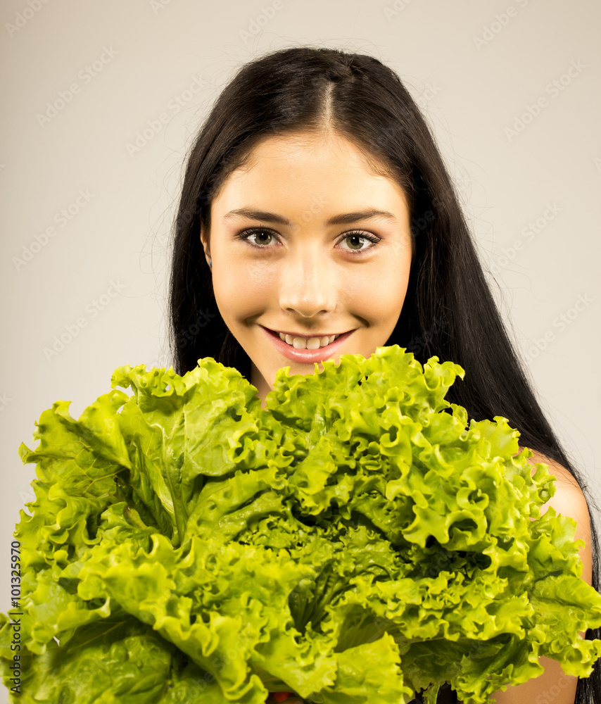 Young woman holding lettuce isolated on grey background Young woman holding lettuce isolated on grey background