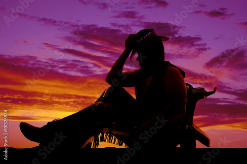silhouette of cowboy sit lean on saddle knees up