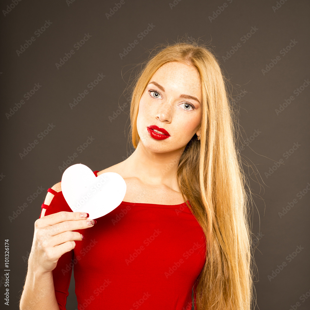 Attractive red-haired girl with a heart in his hands. Black background Attractive red-haired girl with a heart in his hands. Black background