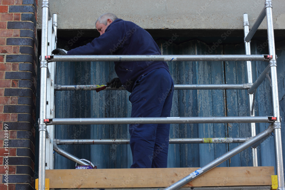 Fototapeta premium A painter and decorator working from a scaffold tower