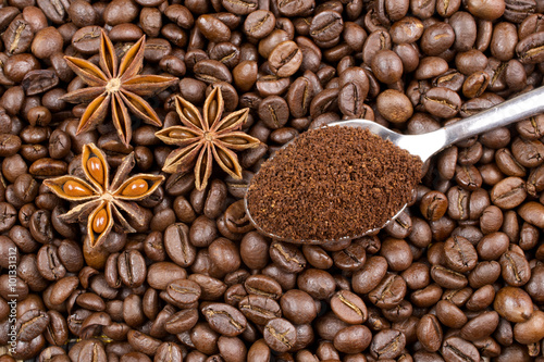 Grounded coffee in the spoon and anise on coffee beans background
