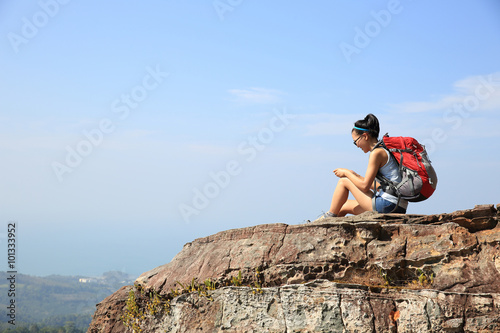young woman backpacker use smartphone on mountain peak