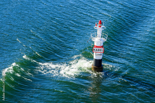 A red and white beacon in the middle of the Baltic sea.