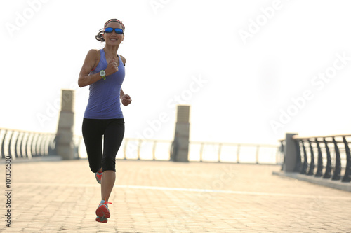 young fitness woman runner running on seaside bridge