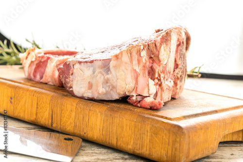 Bistecca alla  fiorentina cruda sul tagliere di legno con rametti di rosmarino photo