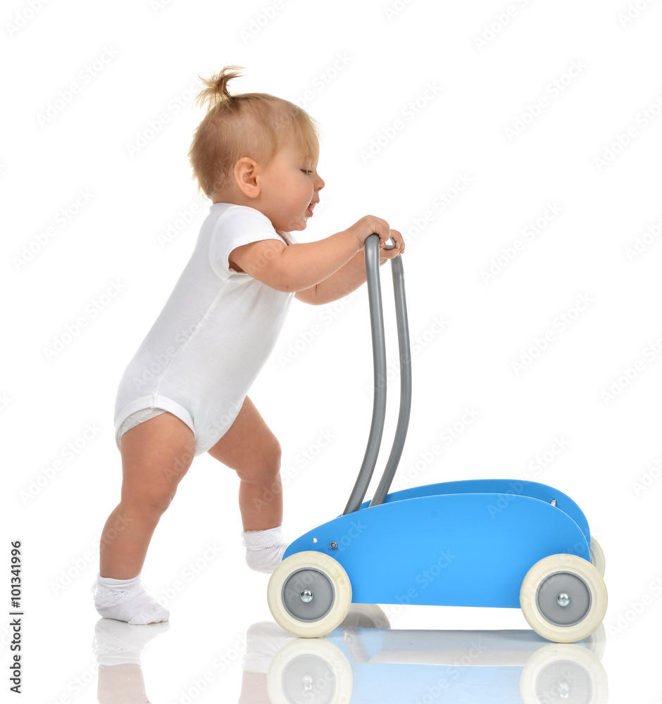 Cute smiling baby girl toddler with toy walker make first steps Cute smiling baby girl toddler with toy walker make first steps