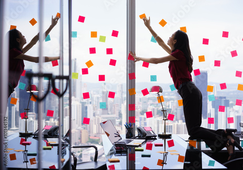 Busy Person Attaching Many Sticky Notes On Large Window