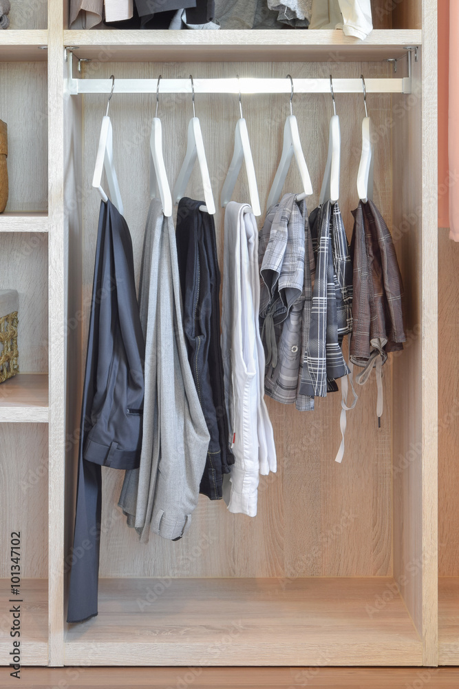 modern closet with row of pants hanging in wooden wardrobe modern closet with row of pants hanging in wooden wardrobe