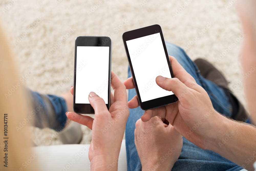 Couple Using Smart Phones At Home