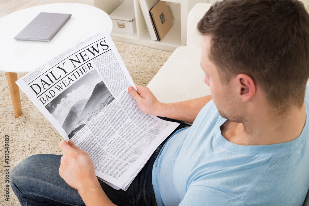 Naklejka premium Man Reading Weather News On Newspaper At Home