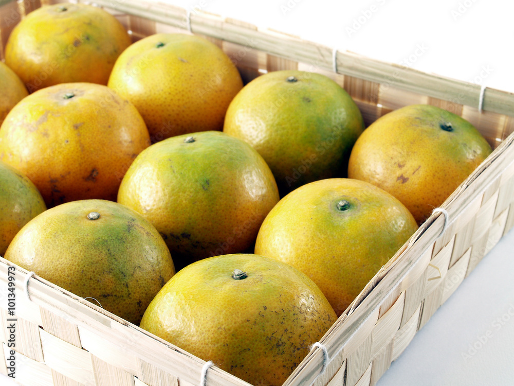 row of oranges arranged in square woven bamboo basket isolated on white row of oranges arranged in square woven bamboo basket isolated on white