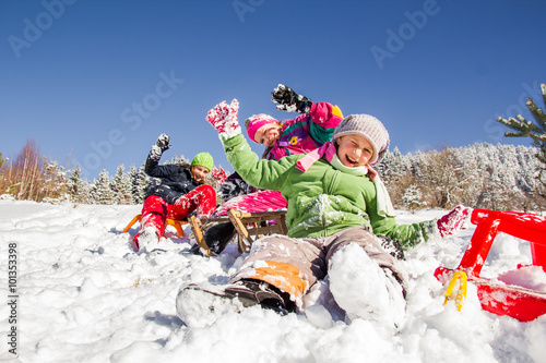 Happy children sledding at winter time. Group of children together.