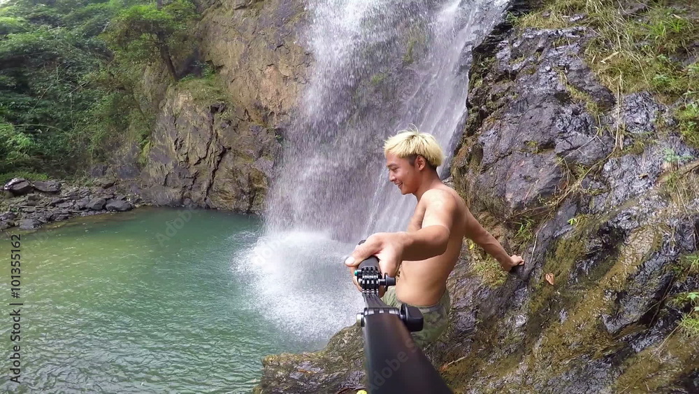 Man walking go to selfie near waterfall.
Man walking go to selfie near waterfall.